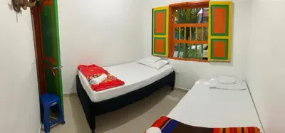 a small room with two beds and a window at casa hostal las palmeras in Guatapé