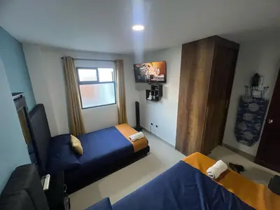 a hotel room with two beds and a tv at Apartamento Ángel Namaste in Bello