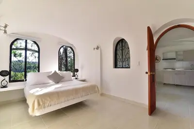 a white bedroom with a bed and two windows at Aldea Bella Boutique in Doradal