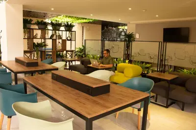 a person sitting in a room with tables and chairs at EcoHub Hotel Medellin in Medellín