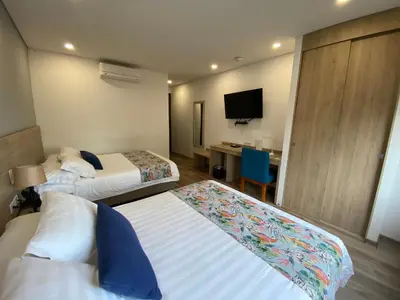 a hotel room with two beds and a desk at EcoHub Hotel Medellin in Medellín