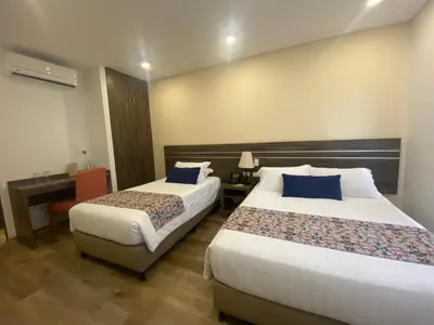 a hotel room with two beds and a desk at EcoHub Hotel Medellin in Medellín
