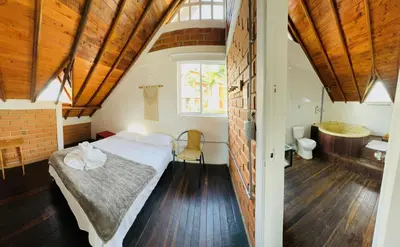 a bedroom with a bed and a bathroom with a sink at La Madriguera in Guatapé