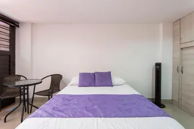 a bedroom with a purple bed and a table at ApartaStudio Calasanz- Cerca Estación Metro Floresta in Medellín