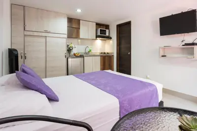 a bedroom with a large bed and a kitchen at ApartaStudio Calasanz- Cerca Estación Metro Floresta in Medellín