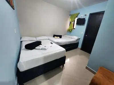 a room with two beds in a room with a door at Hotel Laureles Home in Medellín
