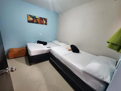 two beds in a small room with blue walls at Hotel Laureles Home in Medellín