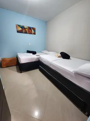 two twin beds in a room with blue walls at Hotel Laureles Home in Medellín
