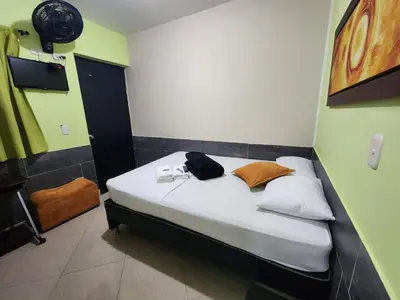a small bedroom with a bed with white sheets at Hotel Laureles Home in Medellín