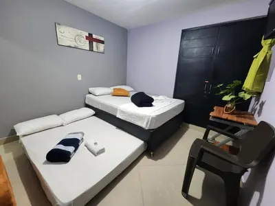 a small room with two beds and a chair at Hotel Laureles Home in Medellín