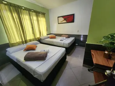 a room with two beds and a table at Hotel Laureles Home in Medellín