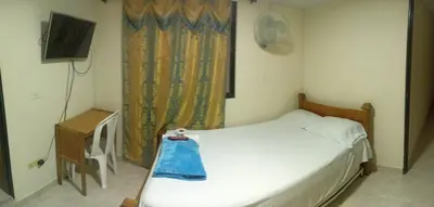 a small bedroom with a bed and a television at Hotel San Vicente in Medellín