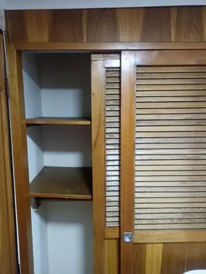 a wooden cabinet with empty shelves in a room at Hotel San Vicente in Medellín