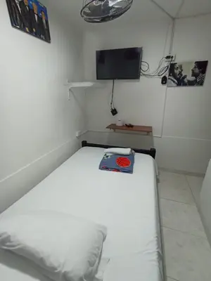a white bed in a room with a tv at Hotel San Vicente in Medellín