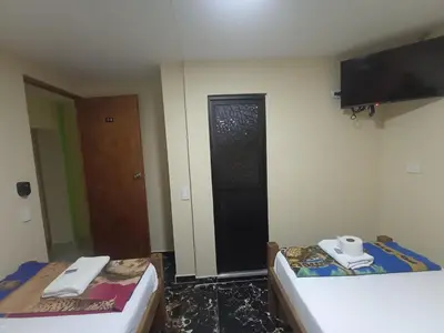 a room with two beds and a door with a television at Hotel San Vicente in Medellín
