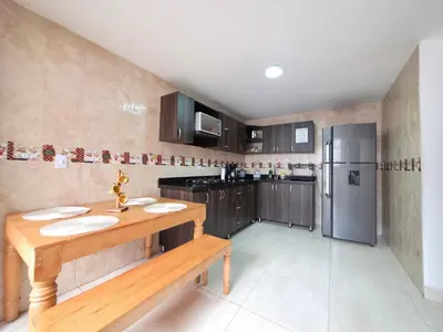 a kitchen with a wooden table and a refrigerator at Casa amplia y cómoda cerca del Estadio y la 70 in Medellín