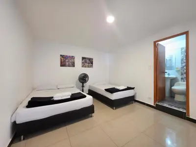 a bedroom with two beds and a bathroom with a mirror at Casa amplia y cómoda cerca del Estadio y la 70 in Medellín