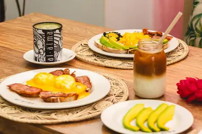 three plates of breakfast food on a wooden table at Hotel Boutique Al Alma in Santa Fe de Antioquia