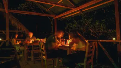 a group of people sitting at a table at night at El Tigrillo Rio Claro by Los Colores Ecoparque in Doradal