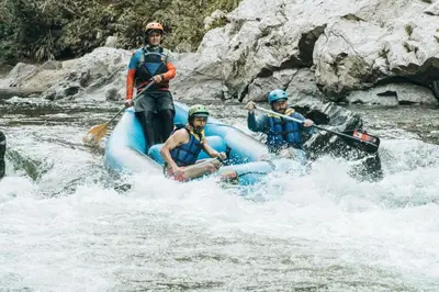 three people rafting on a raft in a river at El Tigrillo Rio Claro by Los Colores Ecoparque in Doradal