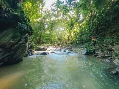 a group of people crossing a river in the jungle at El Tigrillo Rio Claro by Los Colores Ecoparque in Doradal