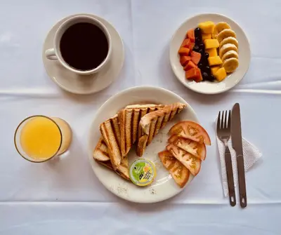 a table with a plate of breakfast food and a cup of coffee at Casa Hotel Solare de la 70 in Medellín