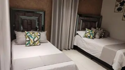 two beds in a room with white sheets and pillows at Casa Hotel Solare de la 70 in Medellín