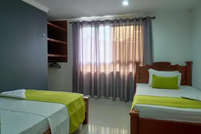 a bedroom with two beds with green sheets and a window at Hotel el imperio in Quibdó