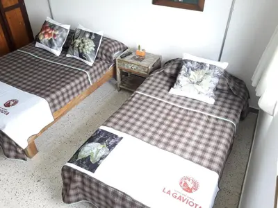two twin beds in a room with a table at Hacienda Cafetera La Gaviota in Chinchiná