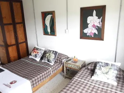 a room with two beds and a table at Hacienda Cafetera La Gaviota in Chinchiná