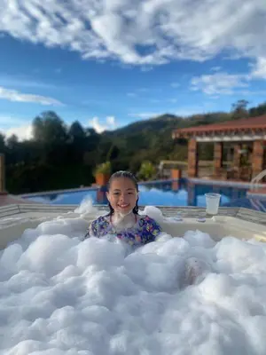 a little girl sitting in a cloud shaped bath tub at Hotel Estaciones in Guatapé