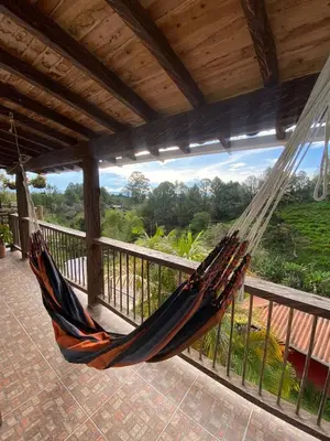 a hammock hanging on a porch with a view at Hotel Estaciones in Guatapé