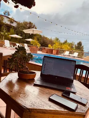 a laptop computer sitting on a wooden table next to a pool at Hotel Estaciones in Guatapé