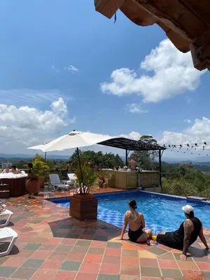 two people sitting next to a swimming pool at Hotel Estaciones in Guatapé