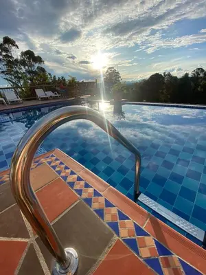 a swimming pool with a hand rail in the water at Hotel Estaciones in Guatapé