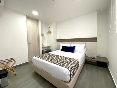 a bedroom with a large white bed with a blue pillow at Seven Inn Hotel in Medellín
