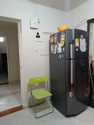 a green chair next to a refrigerator in a room at Pa Pasiar Hostal in Medellín