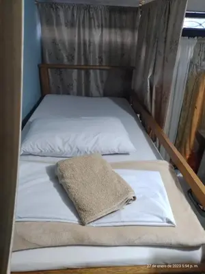 two beds with white sheets and a pillow on them at Pa Pasiar Hostal in Medellín