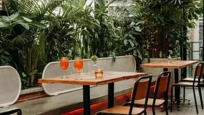 two tables and chairs in a restaurant with plants at The Somos Beats Hotel & Rooftop in Medellín