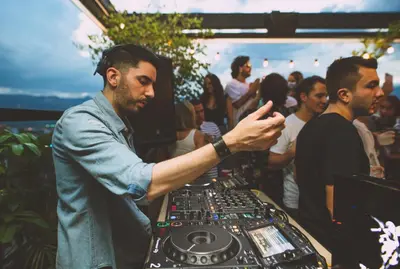 a man standing at a dj booth at a party at The Somos Beats Hotel & Rooftop in Medellín