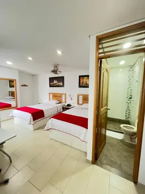 a bedroom with two beds and a bathroom with a toilet at Hotel Portal Central in Medellín