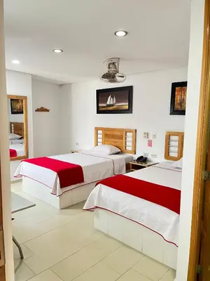 a bedroom with two beds with red and white sheets at Hotel Portal Central in Medellín