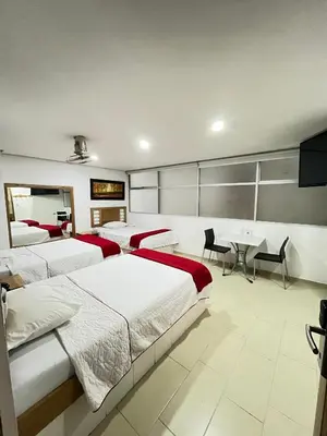 a bedroom with four beds and a table and chairs at Hotel Portal Central in Medellín