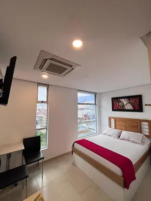 a bedroom with a bed and a desk and some windows at Hotel Portal Central in Medellín