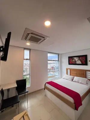 a bedroom with a bed and a desk and some windows at Hotel Portal Central in Medellín
