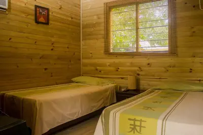 two beds in a room with wooden walls at Hostería Miraflores in Liborina