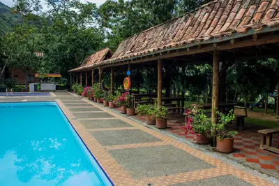 a swimming pool with potted plants and a pavilion at Hostería Miraflores in Liborina