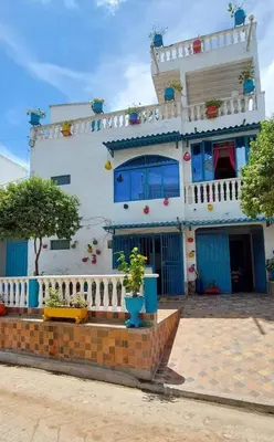 a white house with blue doors and flowers in front of it at El santorini colombiano cabaña in Puerto Triunfo