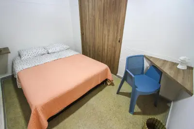 a small bedroom with a bed and a blue chair at Casa Tuvia in Medellín
