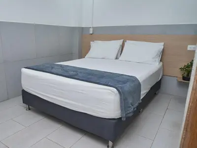 a bedroom with a large bed with white sheets at Stanza Hotel Medellin in Medellín
